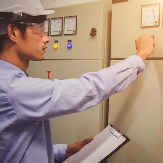Engineer standing in front of the control panel in the control room and write the results of the measurements