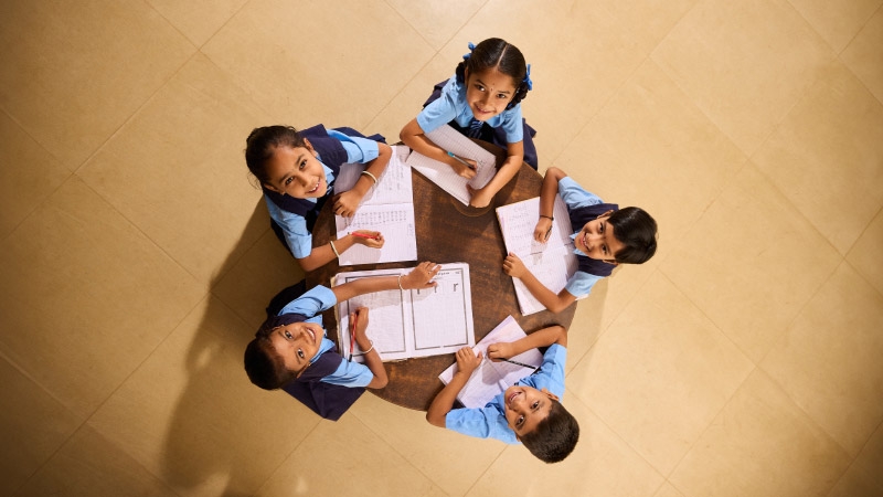 school kids are writing on copy and smiling