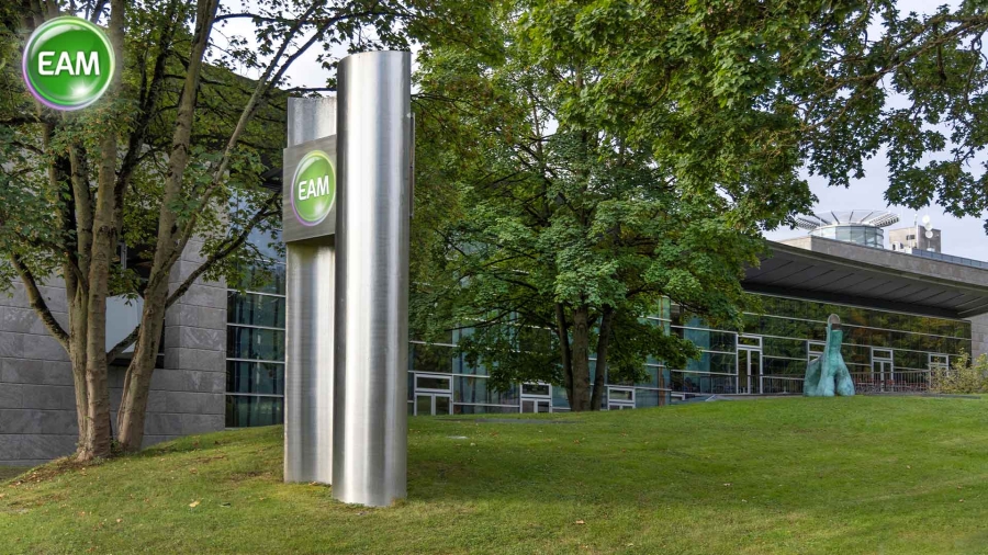 A tall metal pole with a green sign in the middle of a grassy area